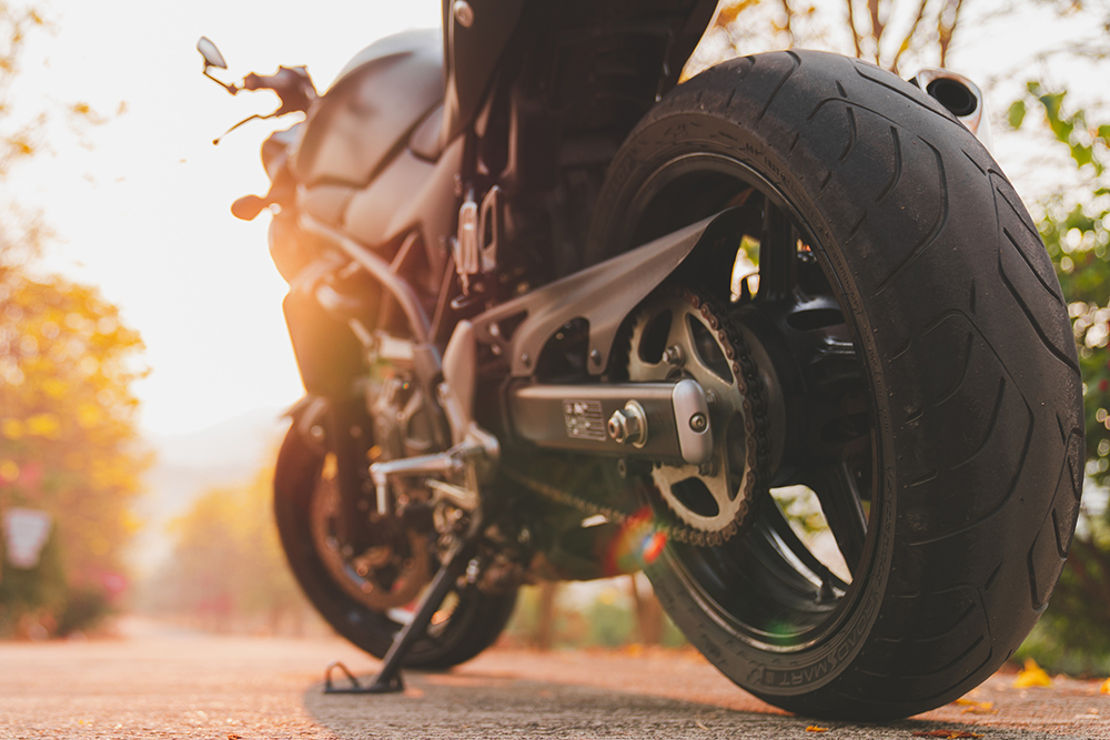 The part of the motorcycle parked on the road is warm ligth. .